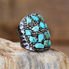 Hematite and turquoise stone ring on a beige background