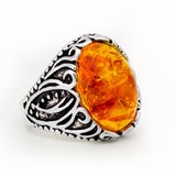 Metal ring with embedded amber resin on a white background.