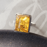 Silver ring with square amber stone on grey background