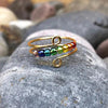 Rainbow pearl rotating ring for women on a gray background.