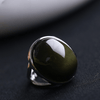 Natural oval obsidian stone ring on a grey background