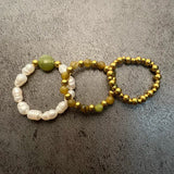 Set of Three Natural Stone Rings in Jade Beads and Stainless Steel on Gray Background