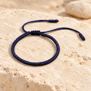 Navy adjustable Tibetan cord bracelet on warm limestone