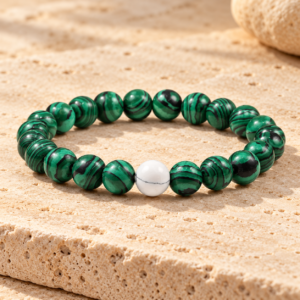 Grünes buddhistisches Armband aus Malachit mit Perlen auf warmem Travertin